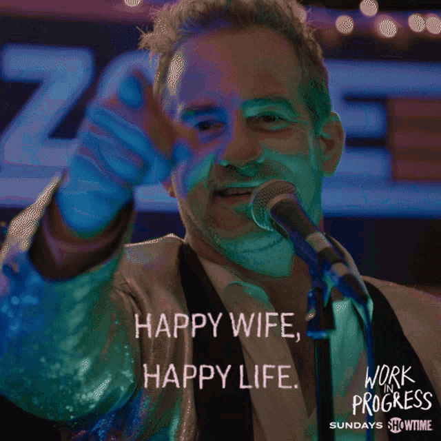 a man singing into a microphone with the words happy wife happy life on the bottom