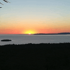 a sunset over a body of water with a small island in the middle