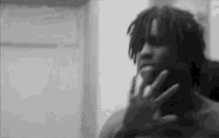 a black and white photo of a man holding his hand to his face .