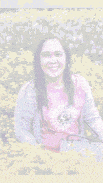 a woman in a pink shirt is surrounded by yellow flowers and a pyramid