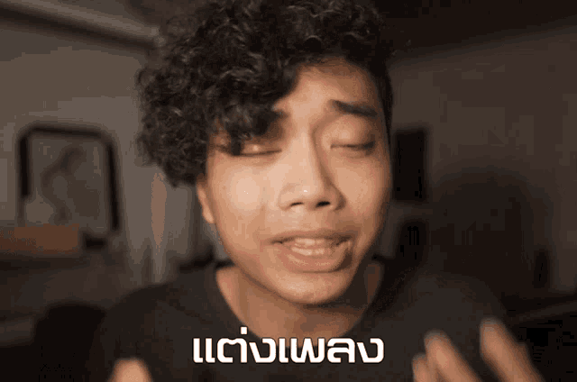 a young man with curly hair is making a funny face with a foreign language written on the bottom of his face