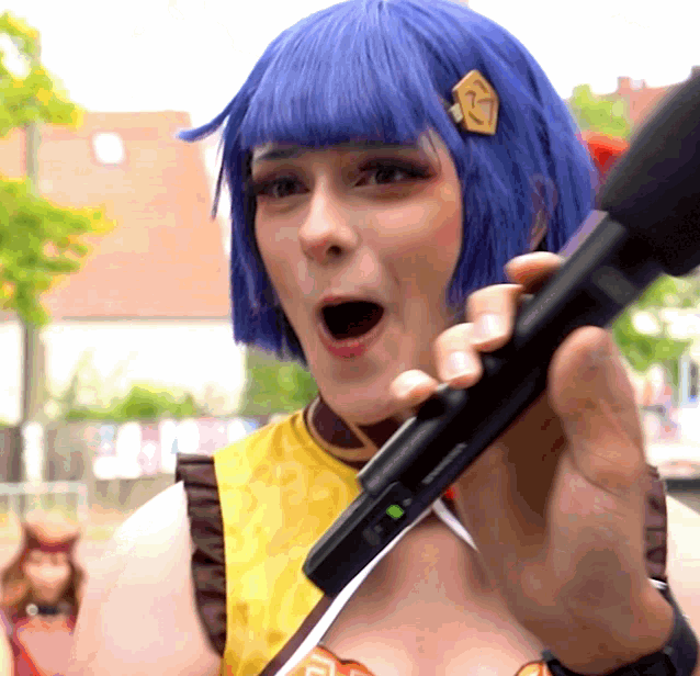 a woman with blue hair is holding a microphone in her right hand