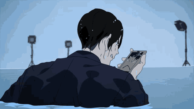 a man is laying in the water looking at a cell phone