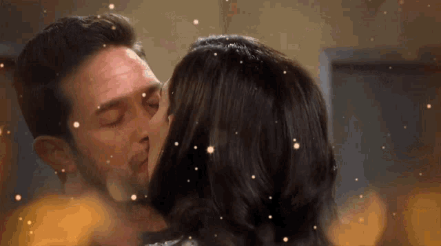 a man and a woman are kissing in front of a window
