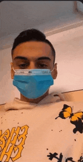 a man wearing a blue face mask and a butterfly sweatshirt .