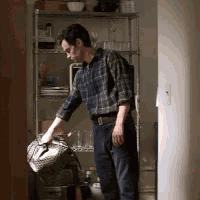 a man in a plaid shirt is holding a bag in front of a shelf