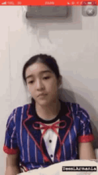 a girl in a suit and bow tie is sitting on a bed .