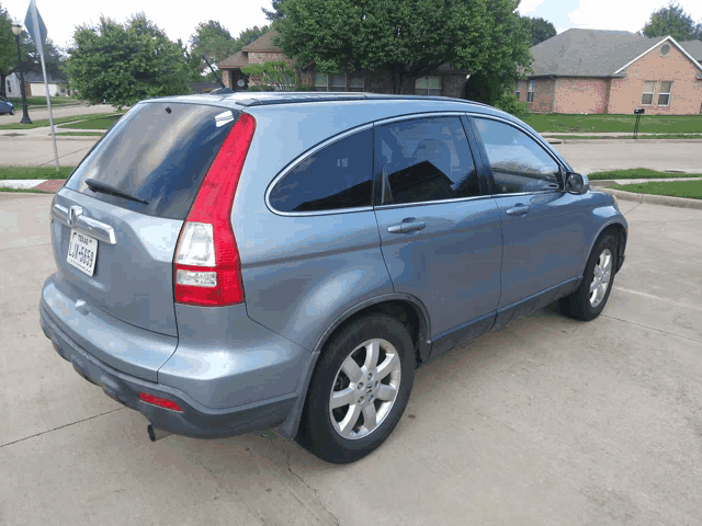a blue honda crv is parked in a parking lot with a house in the background