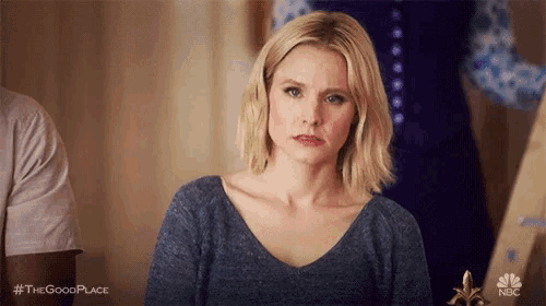 a woman in a blue shirt is making a funny face and looking at the camera .