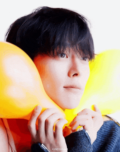 a close up of a person holding a yellow balloon with the name anne written below it