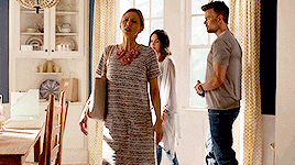 a woman in a striped dress is walking through a room with a man and a woman .