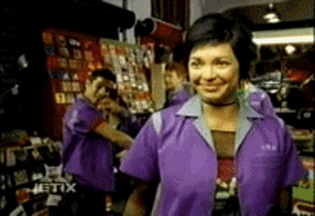 a woman in a purple shirt is smiling in front of a group of people in purple shirts .