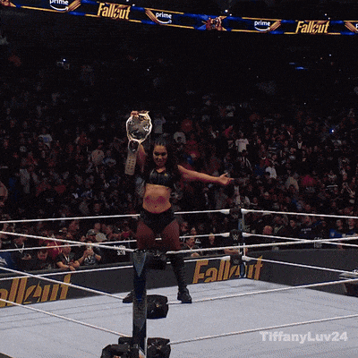 a woman in a wrestling ring holding a championship trophy
