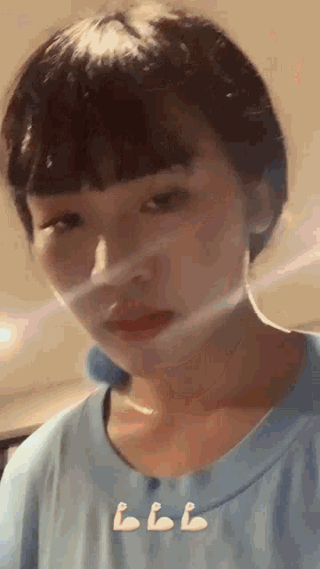 a woman with short hair is wearing a blue t-shirt and making a funny face .