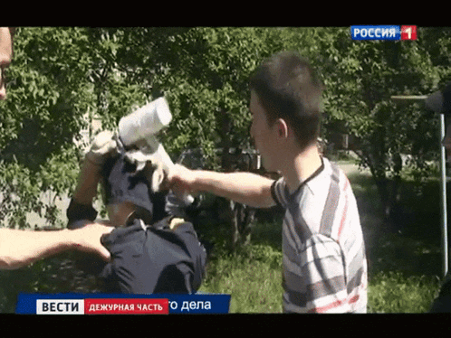 a man is being sprayed with a bottle of water by another man on a tv screen that says вести