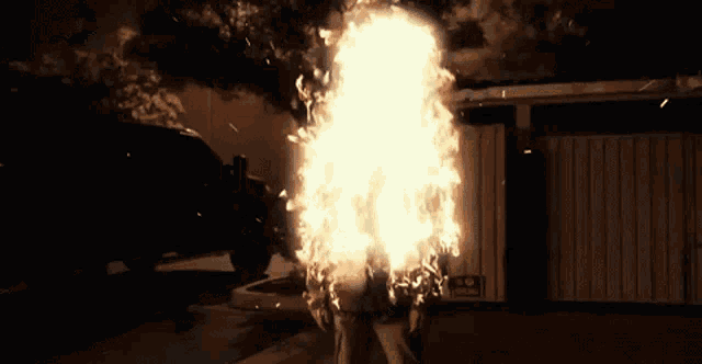 a man is standing in front of a large fireball .