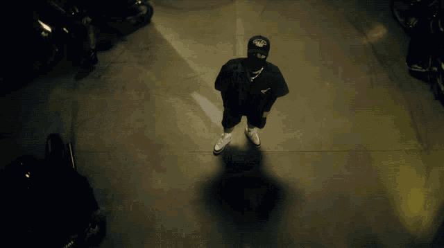 a man wearing a mask is standing in a dark parking garage