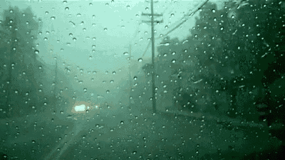 a car is driving down a road in the rain on a rainy day .