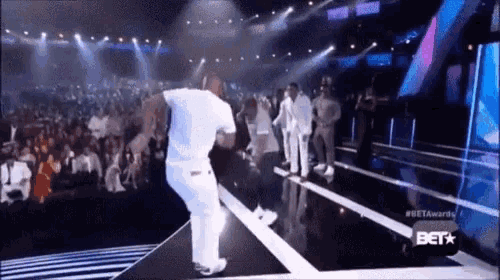 a man in white pants is dancing on a stage in front of a crowd at a bet awards show .