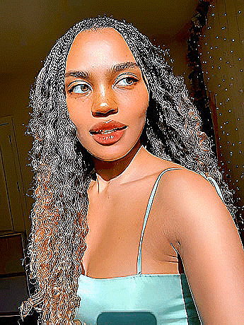 a woman with long curly hair is taking a selfie in a blue dress .