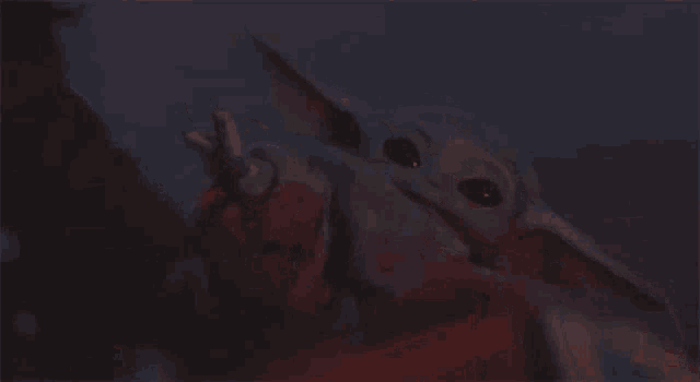 a close up of a baby yoda giving the middle finger .