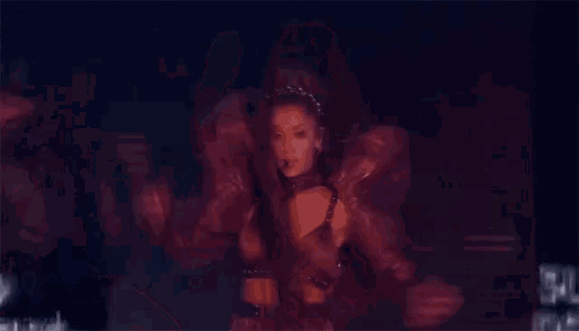 a woman in a red dress is dancing in a dark room behind a fence .