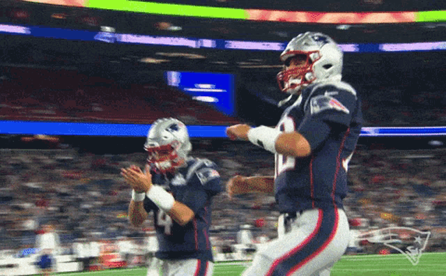 two patriots football players are dancing on the field during a game
