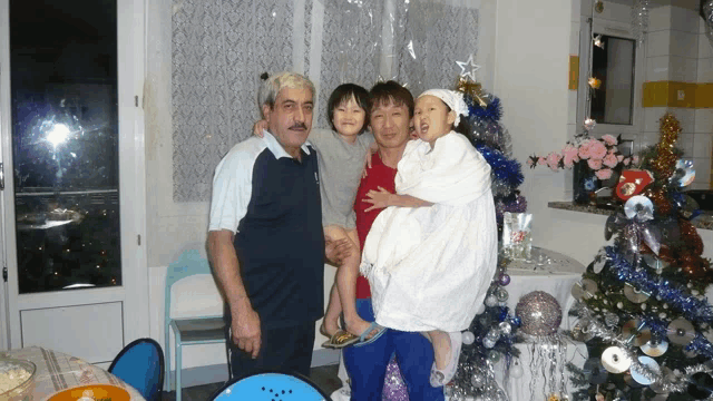 a group of people posing for a picture with a christmas tree in the background