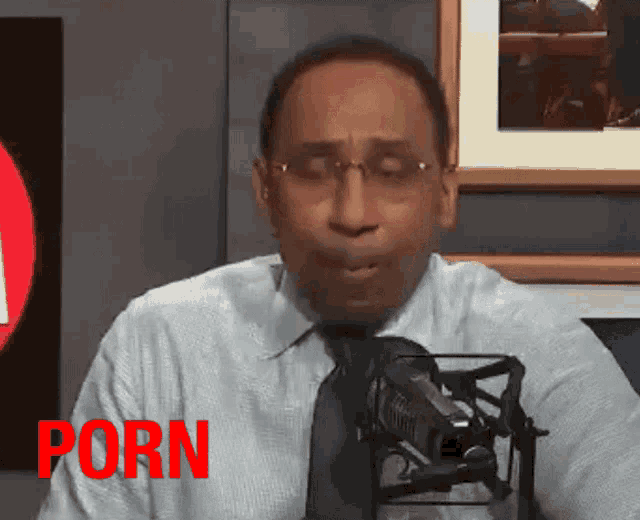 a man sitting in front of a microphone with the word porn in red letters