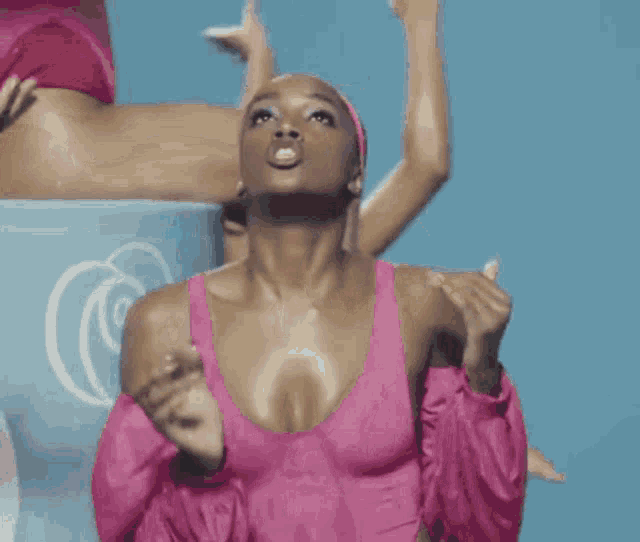 a woman in a pink swimsuit and a pink jacket is making a funny face