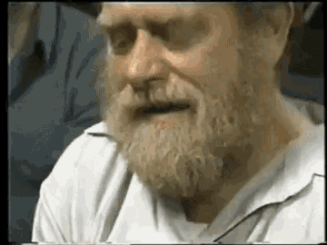 a man with a beard is wearing a white shirt and talking to someone .