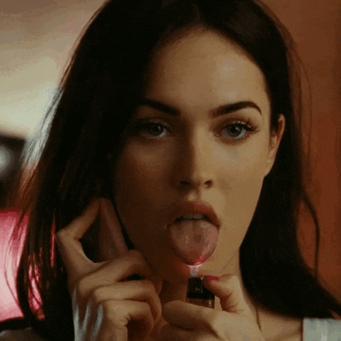 a woman is sticking her tongue out while holding a lighter to her mouth