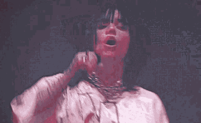 a woman is singing into a microphone while wearing a white shirt .