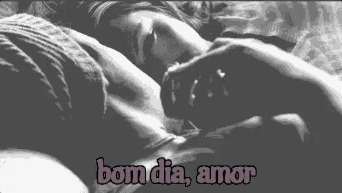 a black and white photo of a woman sleeping on a bed with the words bom dia amor written in pink .