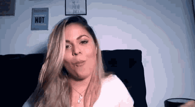 a woman is sitting on a couch making a funny face and looking at the camera .