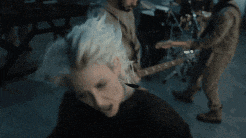 a woman with blonde hair is smiling in front of a drum set