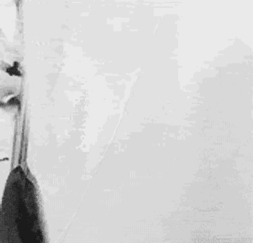 a black and white photo of a scary clown with a bald head and a red nose .