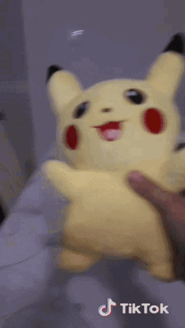 a person is holding a pikachu stuffed animal with a tiktok watermark on the bottom