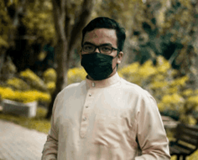 a man wearing a face mask and glasses is standing in a park