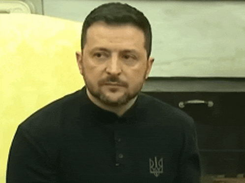 a man with a beard is wearing a black shirt with a ukrainian symbol on it .