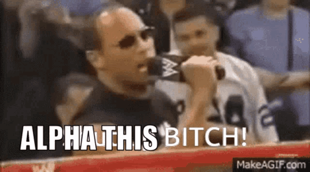 a man is holding a microphone in front of a crowd and saying `` alpha this bitch ! ''