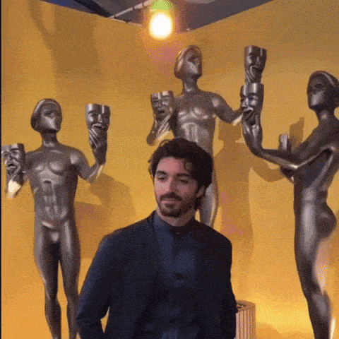 a man in a suit is standing in front of a wall of statues