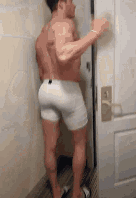 a shirtless man in white underwear is opening a door .