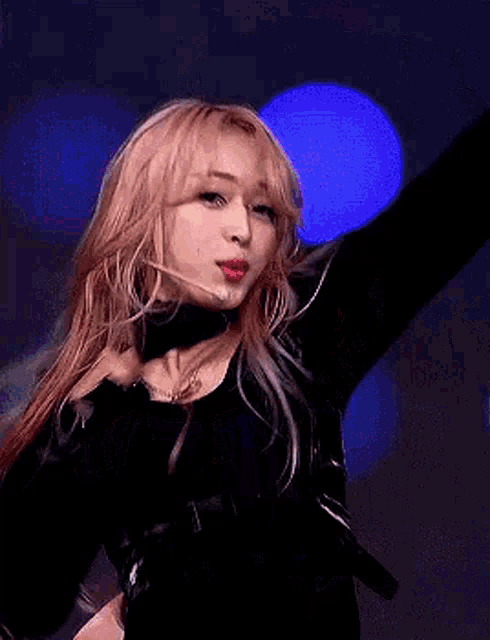 a woman with long blonde hair is holding a microphone in her hand while dancing on a stage .
