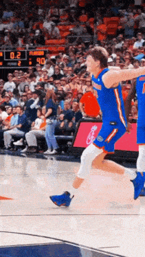 a basketball player is jumping in the air during a game while another player watches .