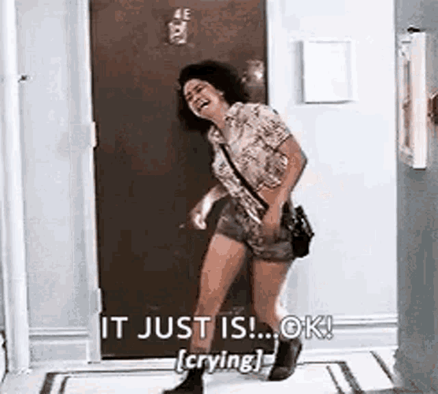 a woman is laughing and crying while standing in a hallway .