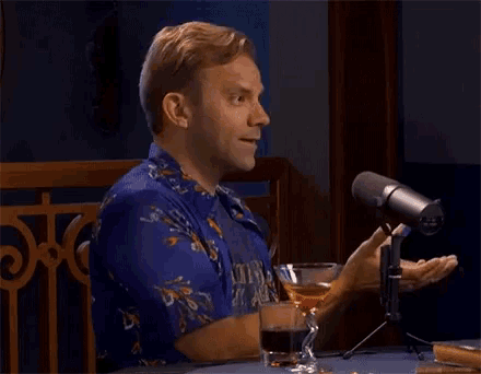a man in a blue shirt is talking into a microphone with the word the on it