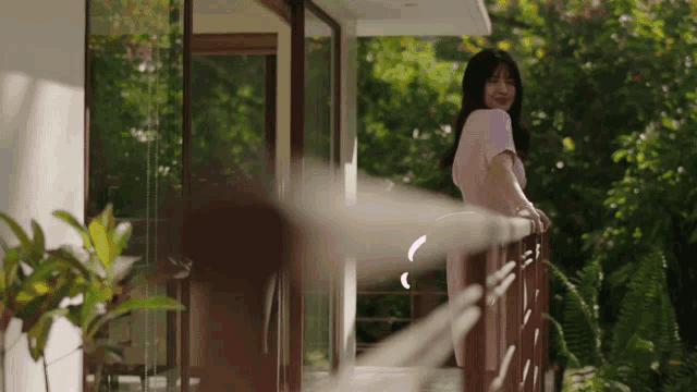 a woman in a pink dress is standing on a balcony overlooking trees