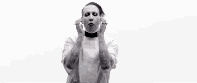 marilyn manson is wearing a white shirt and a choker while standing in front of a white background .