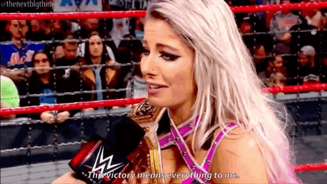 a woman is holding a trophy and talking into a microphone while standing in a wrestling ring .